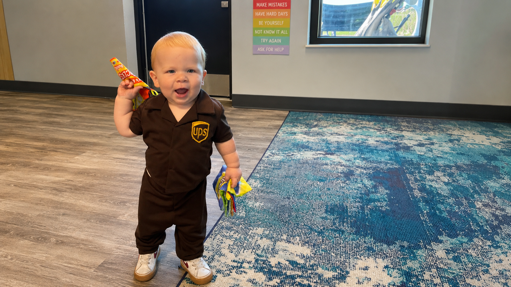 Toddler dressed as a delivery driver holding a package on community helpers dress-up day